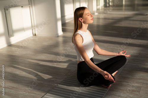 beautiful young woman with a slim figure is engaged in yoga in the hall 