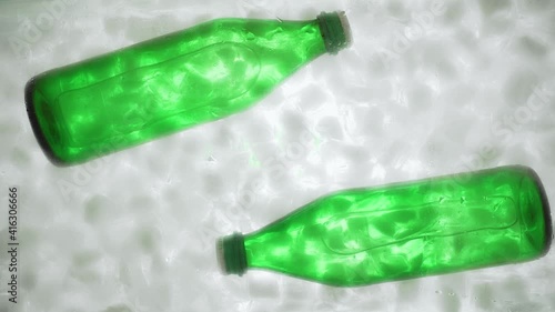 Hand takes out a green bottle with water or soda from a ice water, bottom view. Water bottles in ice cubes. photo