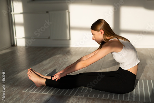 beautiful young woman with a slim figure is engaged in yoga in the hall 