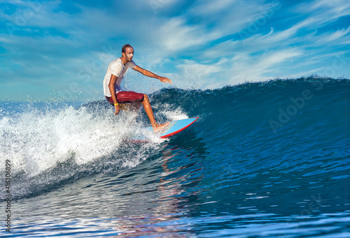 Male surfer on a blue wave at sunny day © trubavink
