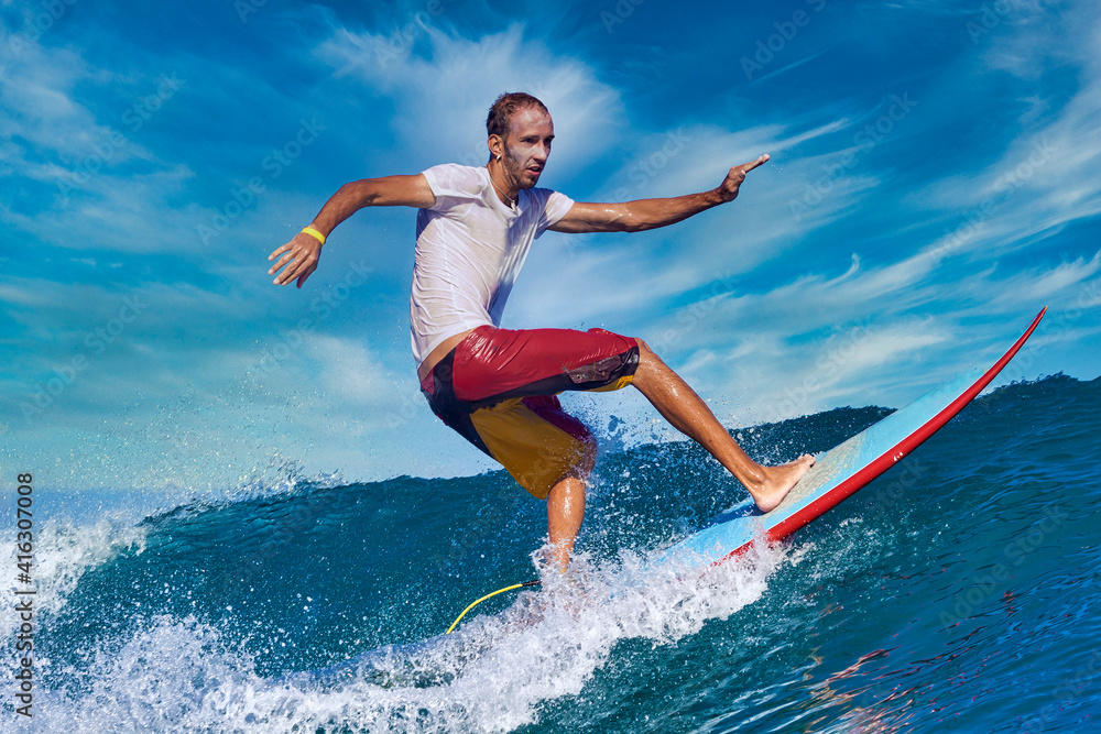 Naklejka premium Male surfer on a blue wave at sunny day