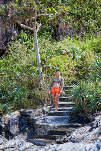 Athletic tattooed guy posing on staits at the jungles photo