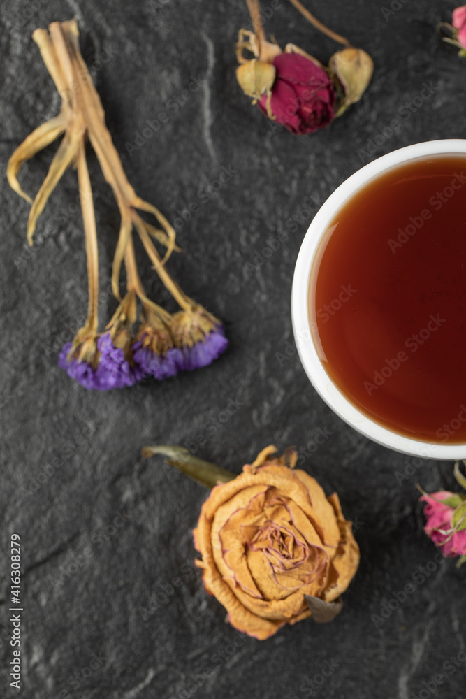 A cup of tea with dried flowers on a black background