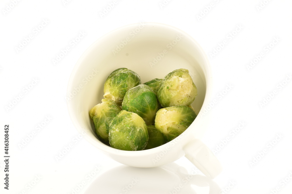 Several frozen organic Brussels sprouts in a ceramic bowl, close-up, isolated on white. Several frozen organic Brussels sprouts in a ceramic bowl, close-up, isolated on white.