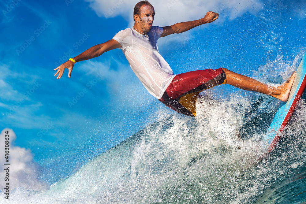 Naklejka premium Male surfer on a blue wave at sunny day