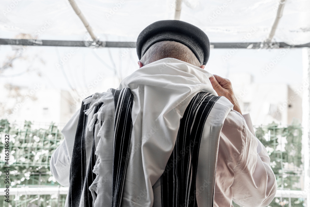 Religious orthodox jew puts on a tallit for prayer. Back view (262)