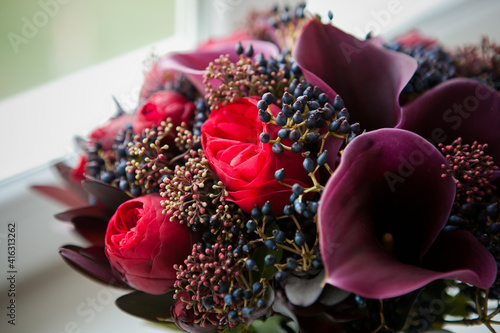 a beautiful and expensive bouquet with red roses and purple calla lilies and dark blue berries. bouquet in the color of wine and marsala