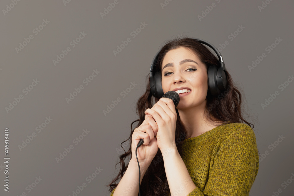 cheerful young woman in casual clothes with headphones sing song in microphone, mock up copy space cheerful young woman in casual clothes with headphones sing song in microphone, mock up copy space