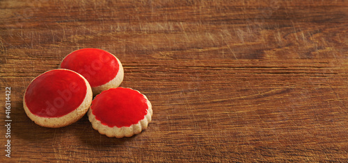 Red coated cookies on an old wooden cutting board photo