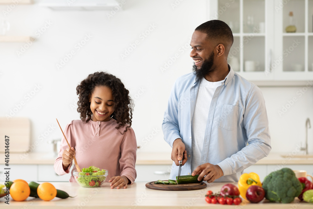 African american father and daughter cooking salad African american father and daughter cooking salad