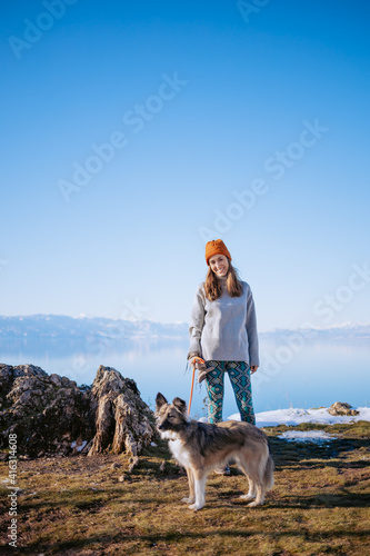 Woman walking her dog on a lake shore in winter © Suteren Studio