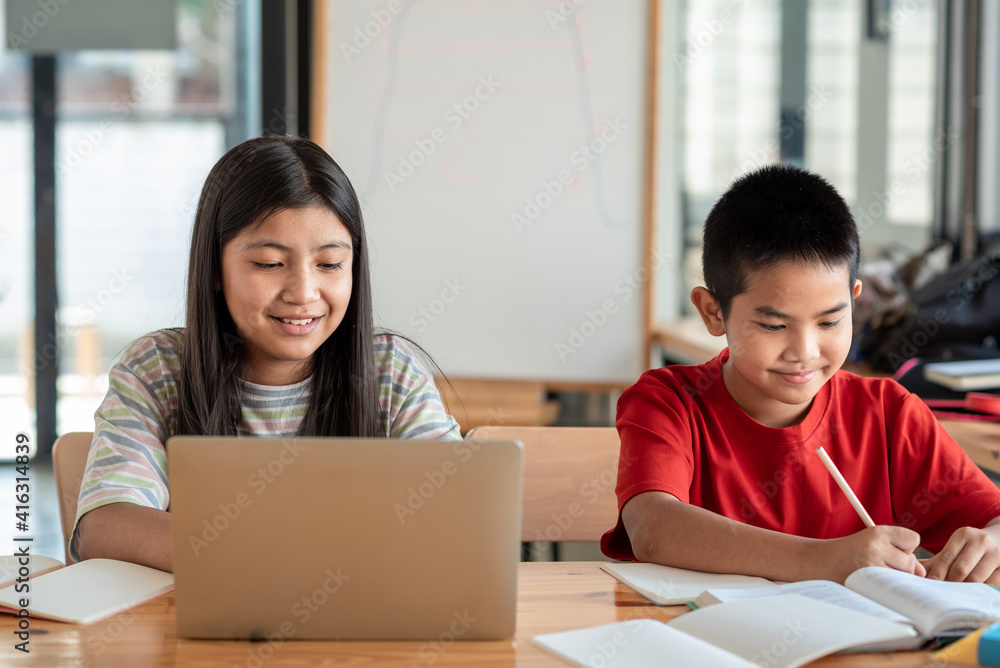 Front view of Asian brothers and sisters, studying online together at home Front view of Asian brothers and sisters, studying online together at home