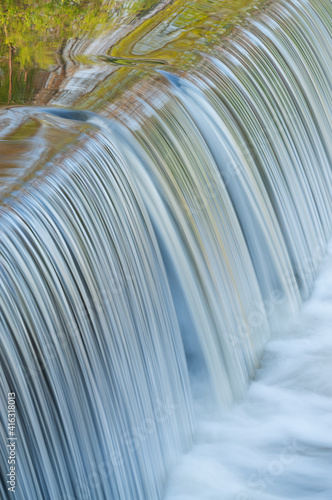 Landscape of the Portage Creek cascade captured with motion blur and with reflections of spring foliage in calm water, Milham Park, Kalamazoo, Michigan, USA