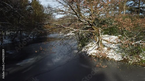 Drohne über dem Bootsteich im Winter im Bürgerpark Bremerhaven, gefrorene Oberfläche und eingeschneiter Baum am Wasser photo