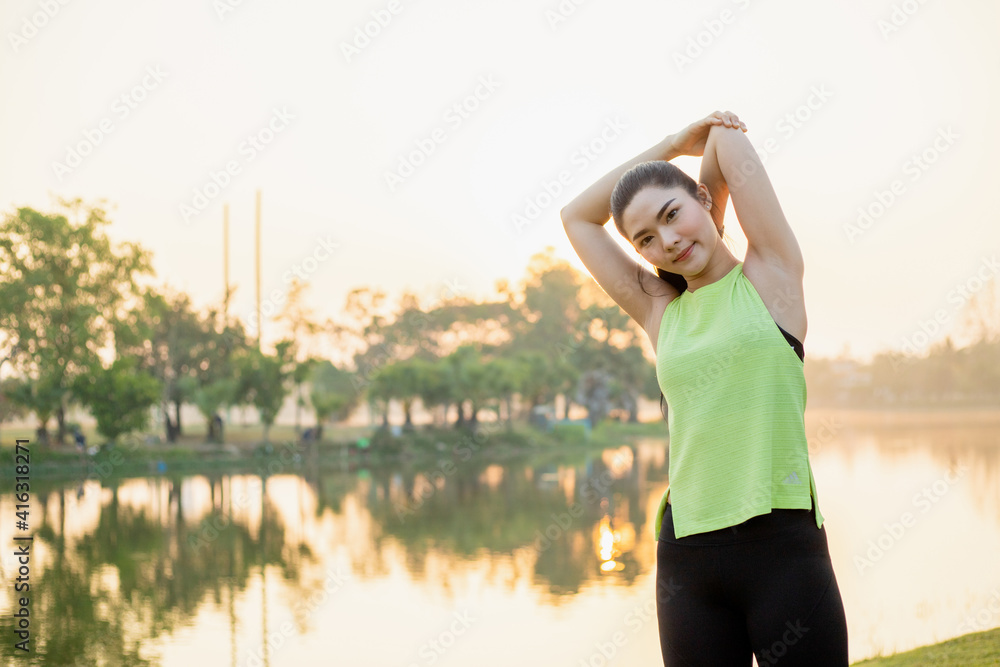 The image of a beautiful woman stretching her arms outdoors in the park in the morning before exercise