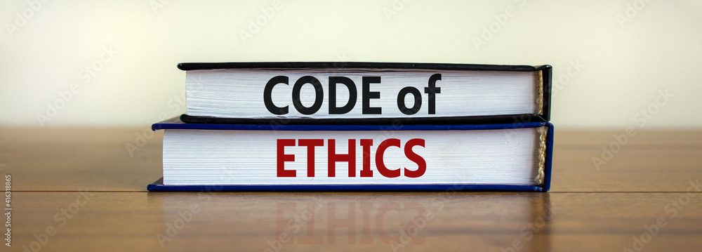 Code of ethics symbol. Concept words 'Code of ethics' on books on a beautiful wooden table, white background. Business and code of ethics concept. Copy space.