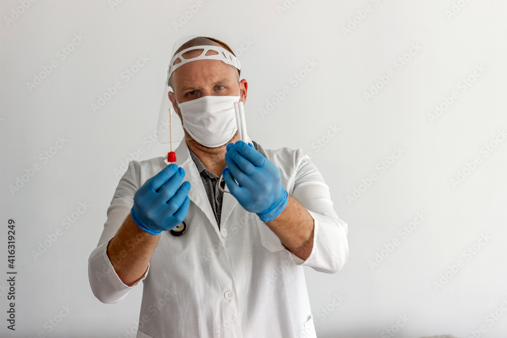Male doctor in protective suit holding and showing covid-19 tube test and sampling swab. Lab technician holding swab collection kit. Doctor showing tube test and sampling swab with protective gloves. Male doctor in protective suit holding and showing covid-19 tube test and sampling swab. Lab technician holding swab collection kit. Doctor showing tube test and sampling swab with protective gloves.