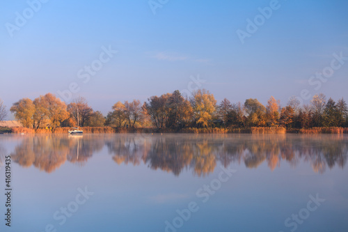 drzewa odbijające się w jeziorze, jesienny poranek