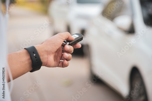 Man's hand pressing on the white car remote key