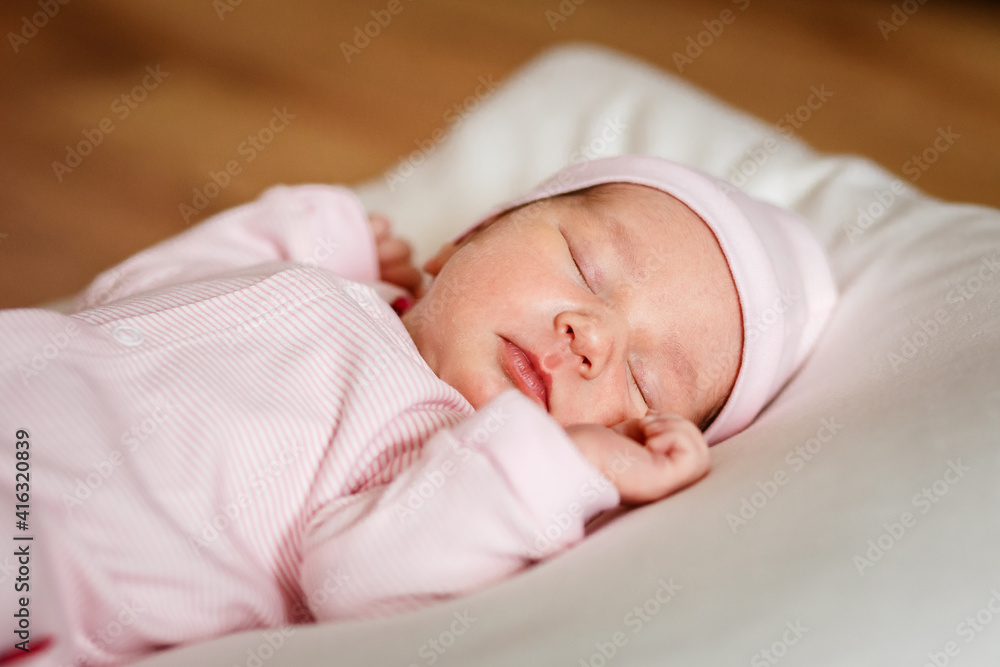 newborn baby of less than a week in a pink jumpsuit sleeps on a white plaid. Cute Little Close newborn baby of less than a week in a pink jumpsuit sleeps on a white plaid. Cute Little Close