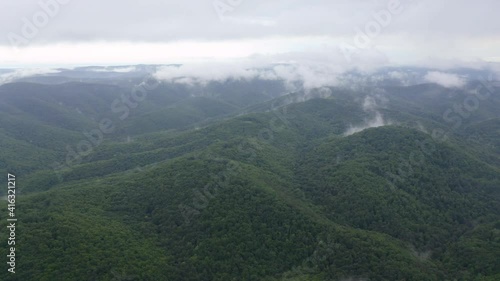 Drone flight over green mountain slopes with creeping spring mists above them, Strandzha Mountain, Bulgaria