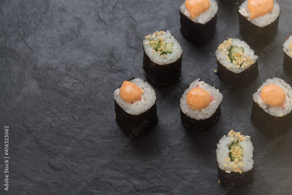 Rolls on a stone platter. Roll with cucumber, cheese sprinkled with sesame seeds. view from 45 degrees Rolls on a stone platter. Roll with cucumber, cheese sprinkled with sesame seeds. view from 45 degrees