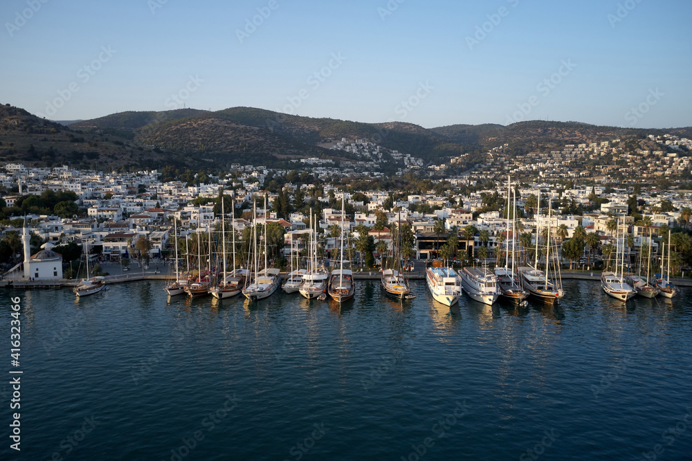 Bodrum city and harbor view. Drone view of sea, ships and city with beautiful blue sky in the background. Resort town at Mediterranean sea.
