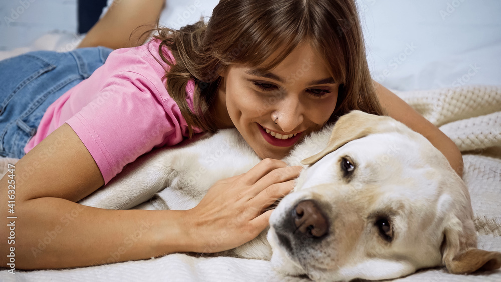 happy young woman lying with golden retriever dog on bed happy young woman lying with golden retriever dog on bed