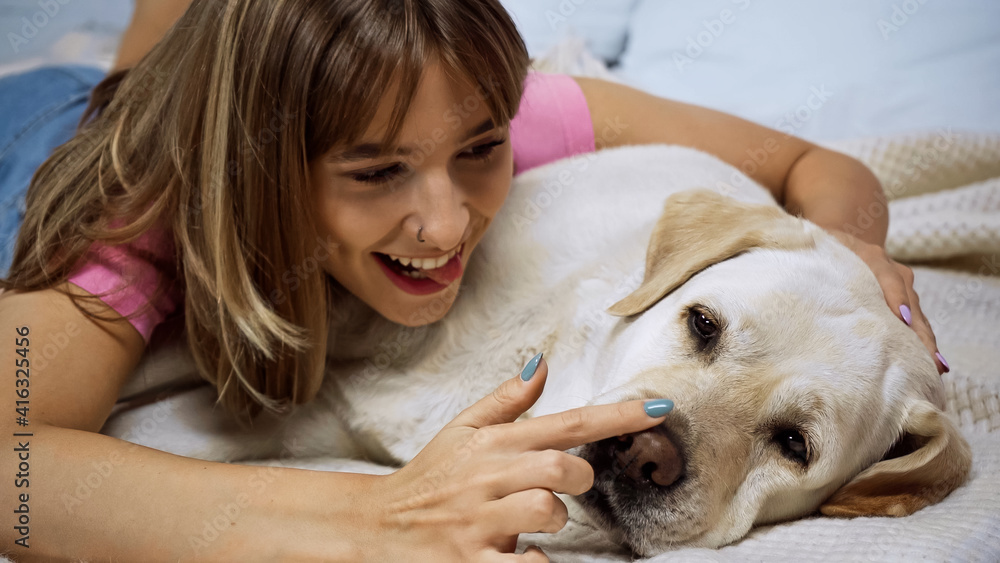 happy young woman touching nose of golden retriever dog on bed happy young woman touching nose of golden retriever dog on bed