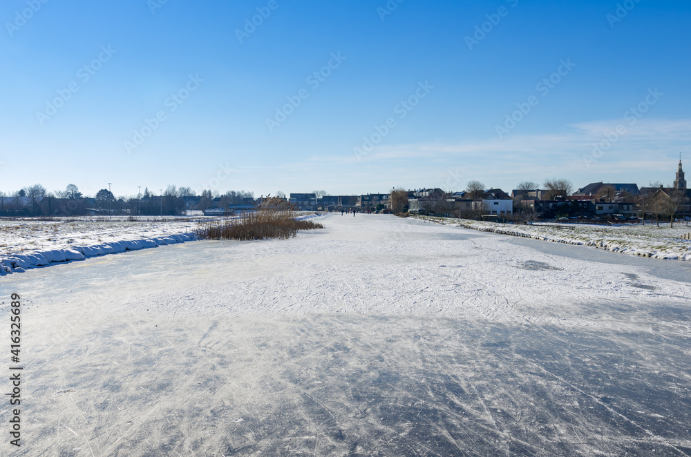 frozen and snowy Dutch landscape with clear blue sky. frozen water in canal