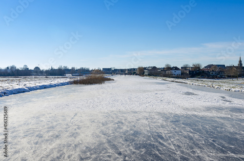 frozen and snowy Dutch landscape with clear blue sky. frozen water in canal © Robin