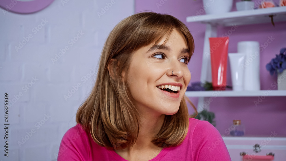 happy young woman with piercing smiling while looking away at home happy young woman with piercing smiling while looking away at home
