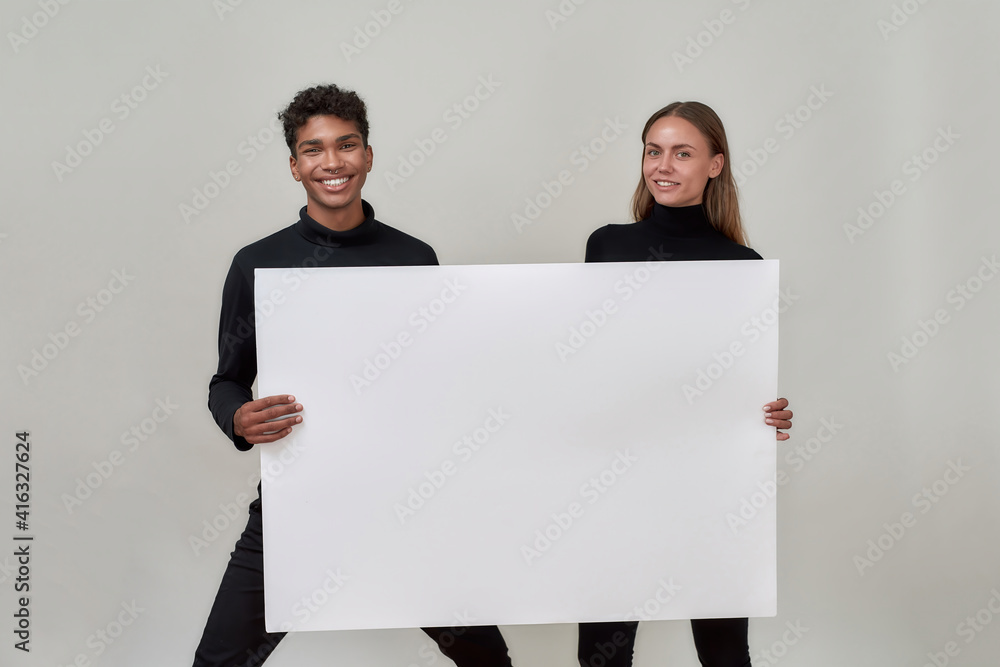 Cheerful young mixed race couple holding placard mockup Cheerful young mixed race couple holding placard mockup