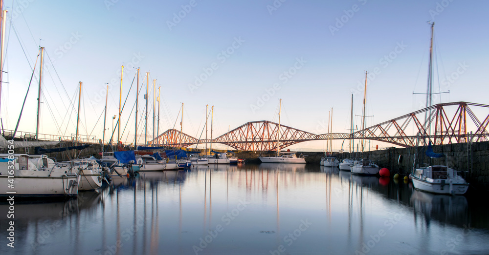 The Red Forth Rail Bridge in the background and few boats from the boat club during sunrise.
