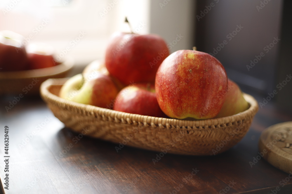 Jabłka czerwone w wiklinowym koszyku na drewnianym stole ciemnym - obrazy, fototapety, plakaty 