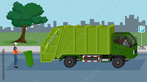 Transportation of garbage truck green color with driving on the asphalt road.  The worker dragged the trash in the back. Backdrop is a wide grass and trees with a silhouette of a large city.