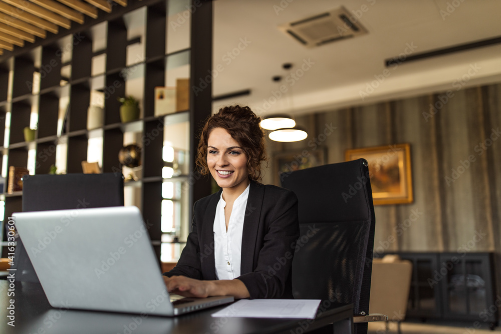 © bnenin - Successful businesswoman working on laptop, portrait.
