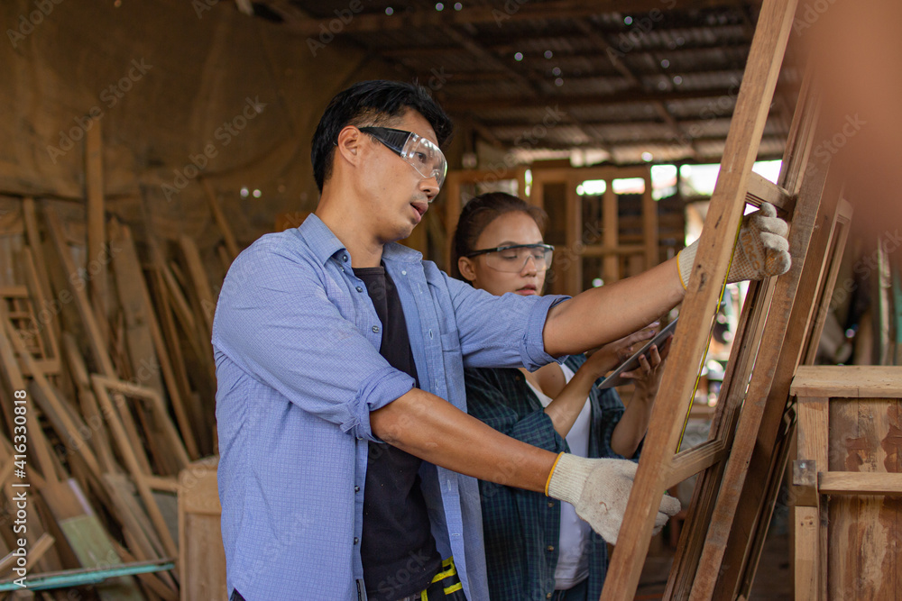 Two asian carpenters in a construction workshop. business man and woman working together woodwork Two asian carpenters in a construction workshop. business man and woman working together woodwork