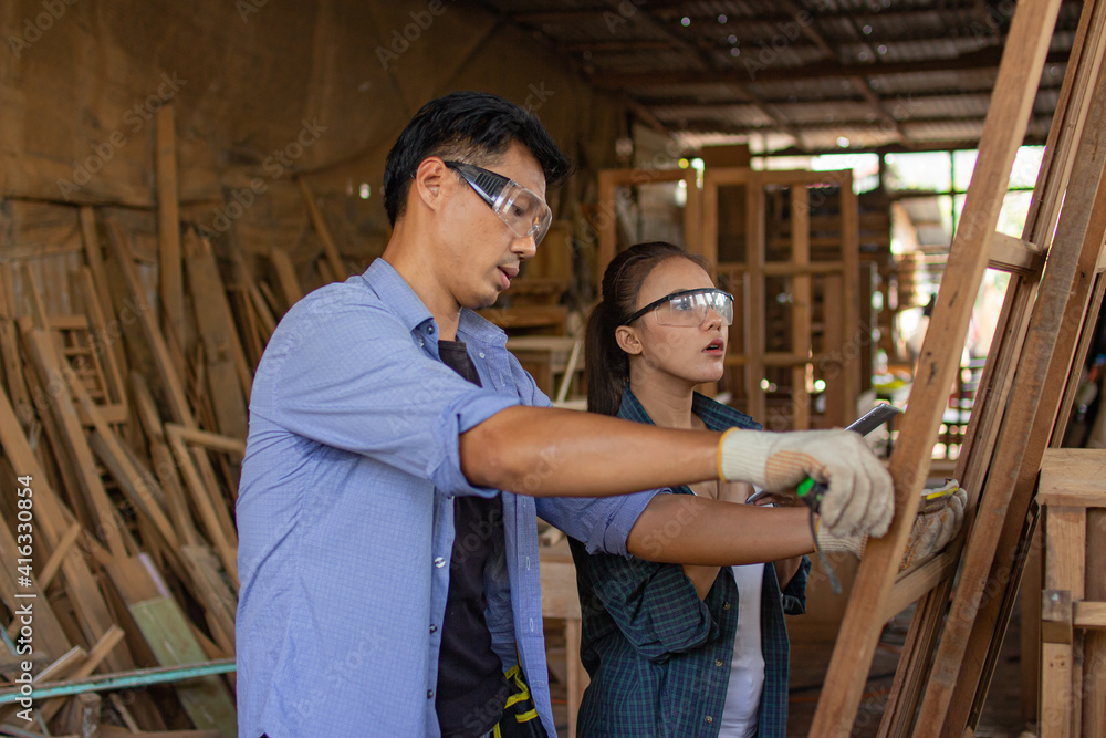Two asian carpenters in a construction workshop. business man and woman working together woodwork