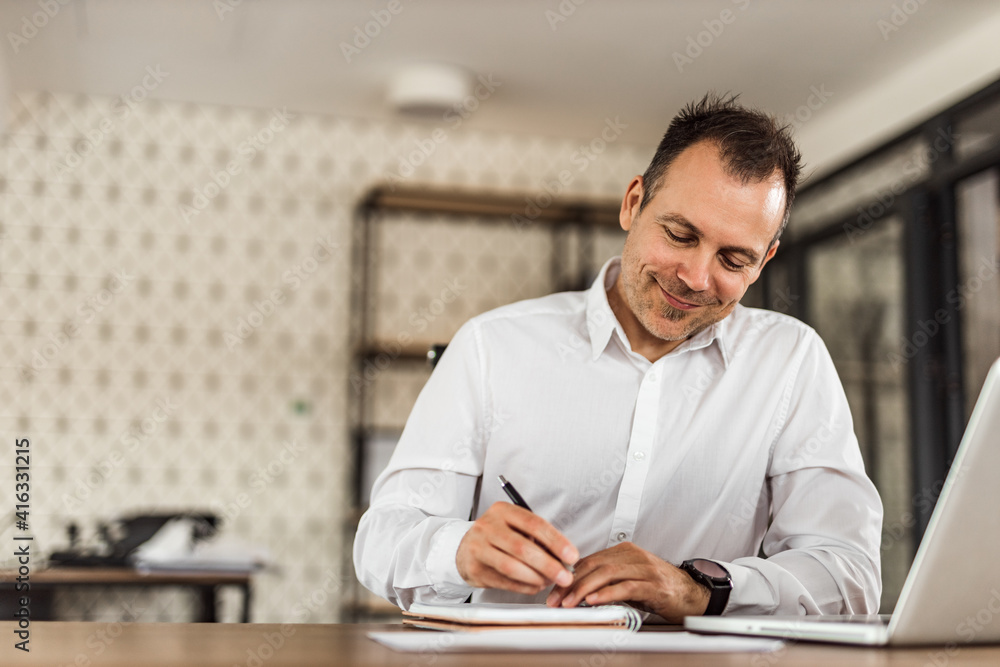 Front view portrait of a charming businessman taking notes. Front view portrait of a charming businessman taking notes.
