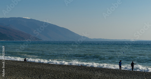 Fishermen are fishing in Black Sea. View of Caucasian mountains in Abkhazia from Russian side. December winter sea in southern resort of Russia. Sunny winter day. Sochi  Russia - December 08  2020