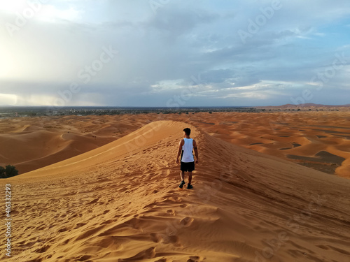 Man walking in the highest dune of the sahara desert.