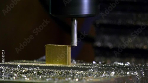 Milling a golden brass block on a powered machine while residual sparks flying around. Close up shot