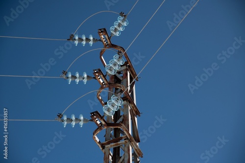 metal electricity pole with glass insulator and clear blue sky close up photo