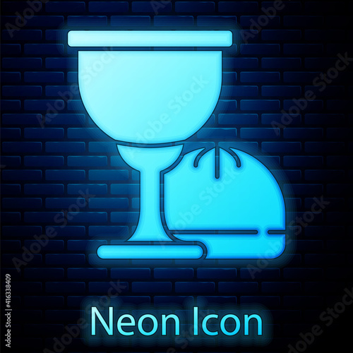 Glowing neon Holy grail or chalice icon isolated on brick wall background. Christian chalice. Christianity icon. Vector.