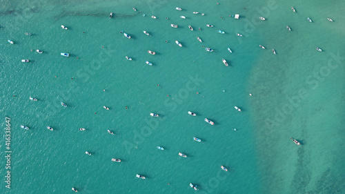 Local fishing boats at sea. Beautiful turquoise water on a clear day. Bird's eye view of the ocean with various boats.
