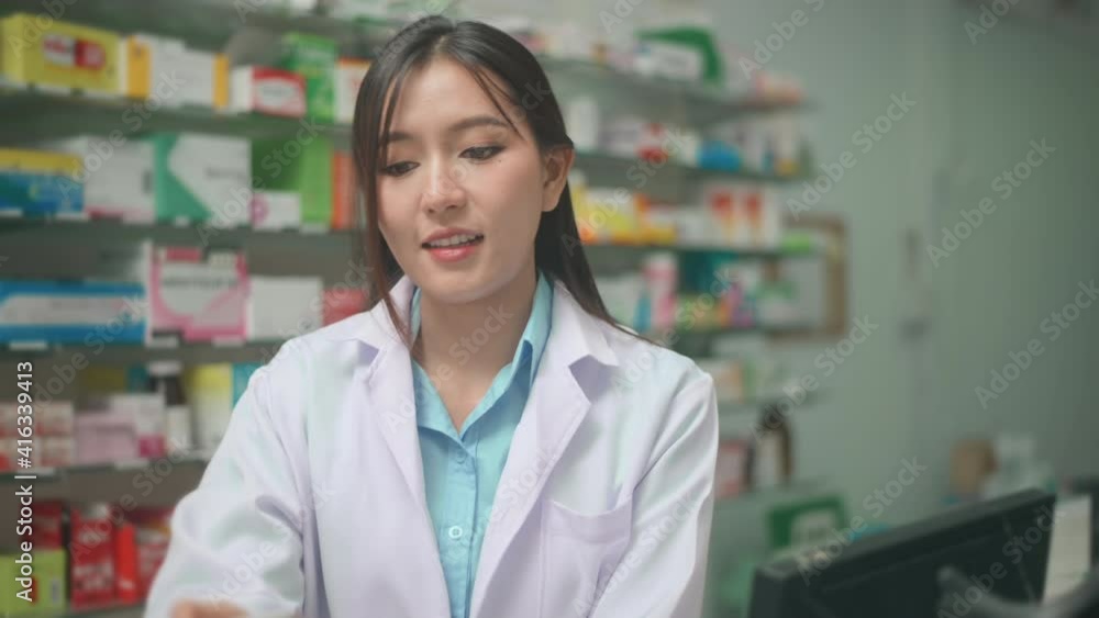 An asian woman pharmacist wearing lab coat in a modern pharmacy drugstore, selecting a medicine for customer. An asian woman pharmacist wearing lab coat in a modern pharmacy drugstore, selecting a medicine for customer.