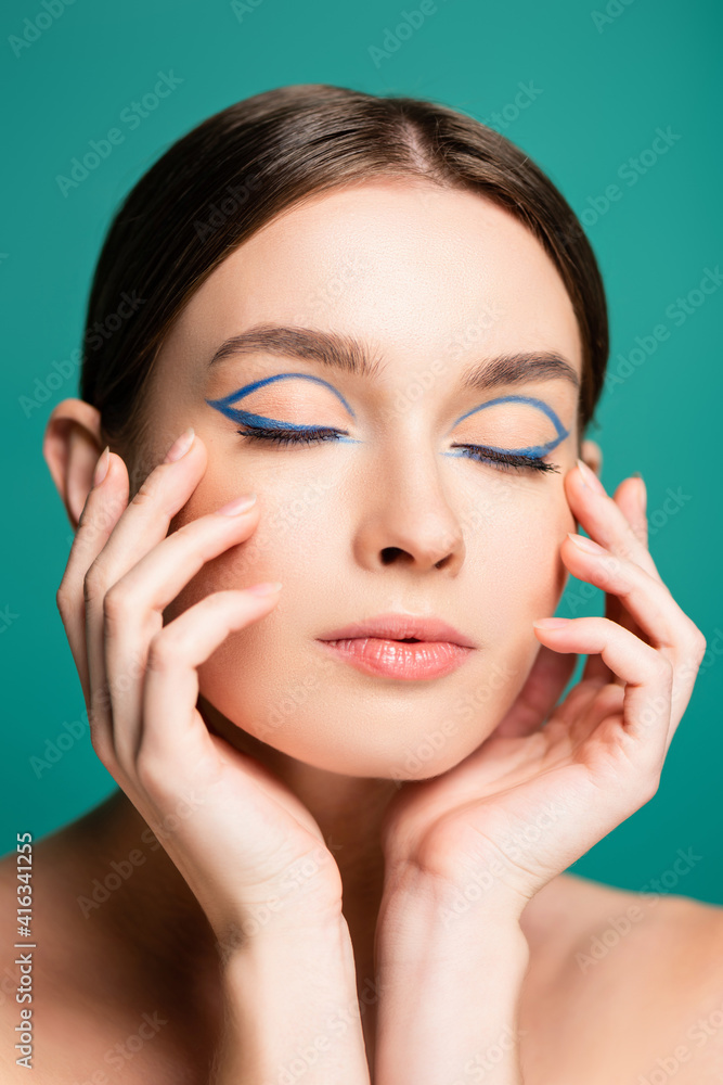 charming woman with blue eyeliner in closed eyes posing with hands near face isolated on green