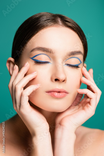 charming woman with blue eyeliner in closed eyes posing with hands near face isolated on green photo