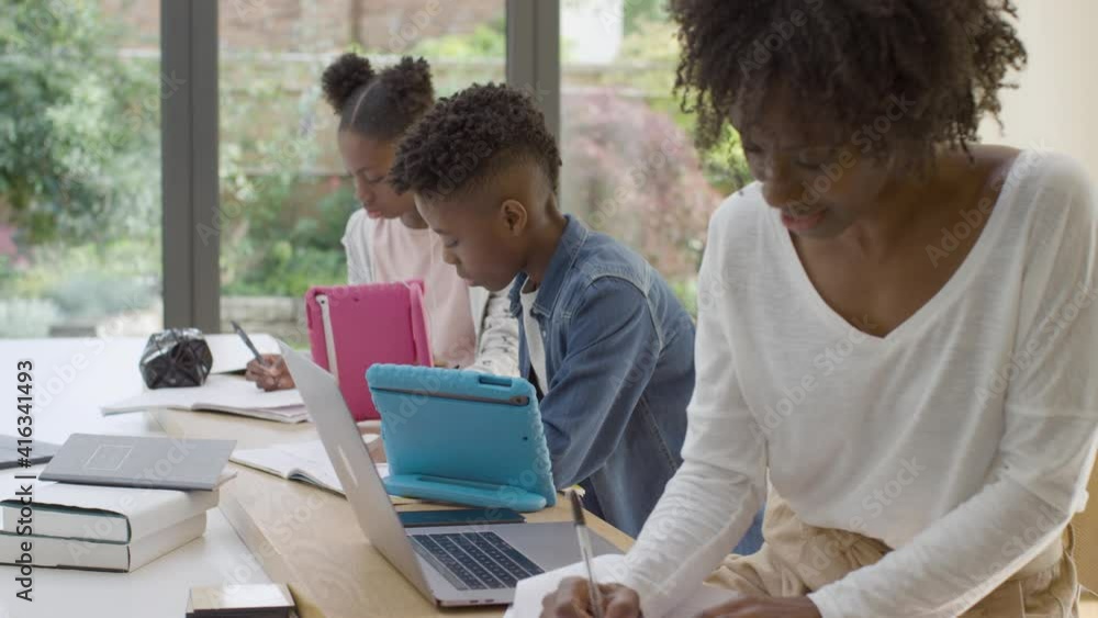 Mother Working from Home While Her Children Do School Work Next to Her Mother Working from Home While Her Children Do School Work Next to Her